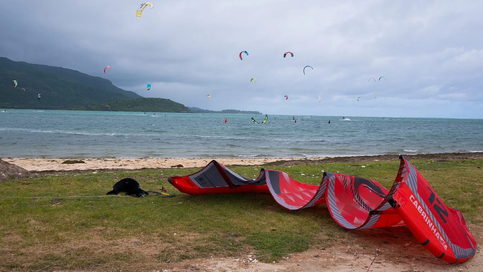 Ailes de kitesurf posées sur une plage de la côte sud-ouest de l'île Maurice, avec de nombreux kitesurfeurs au large