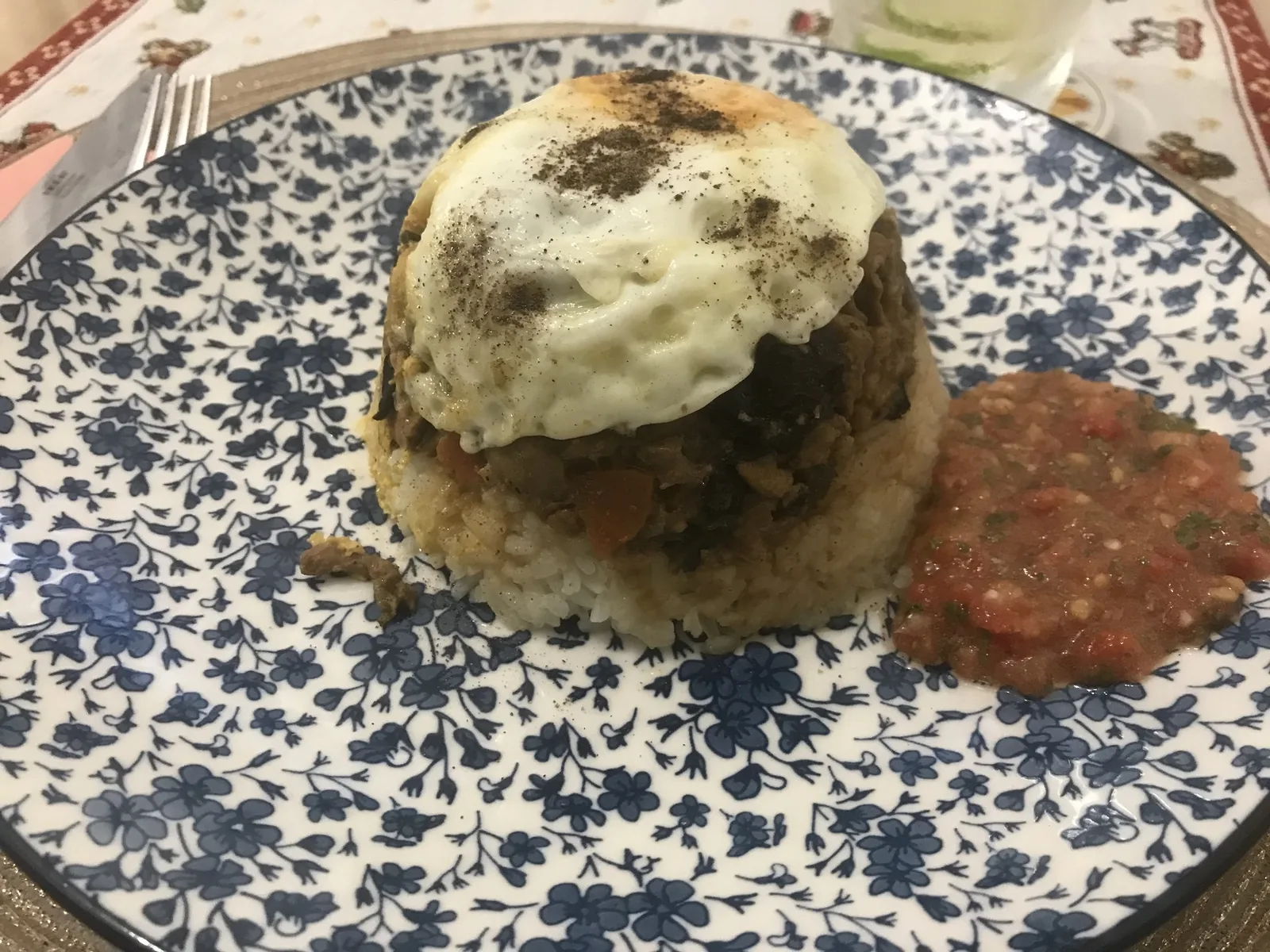 Bol renversé : riz et garniture démoulés, surmontés d'un œuf, avec une sauce tomate