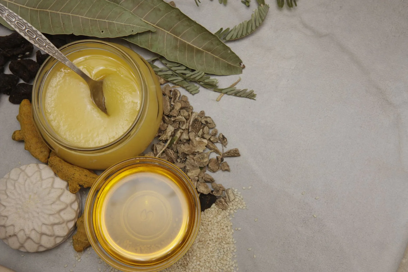 Ghee, huile, curcuma et herbes séchées disposés pour un soin ayurvédique