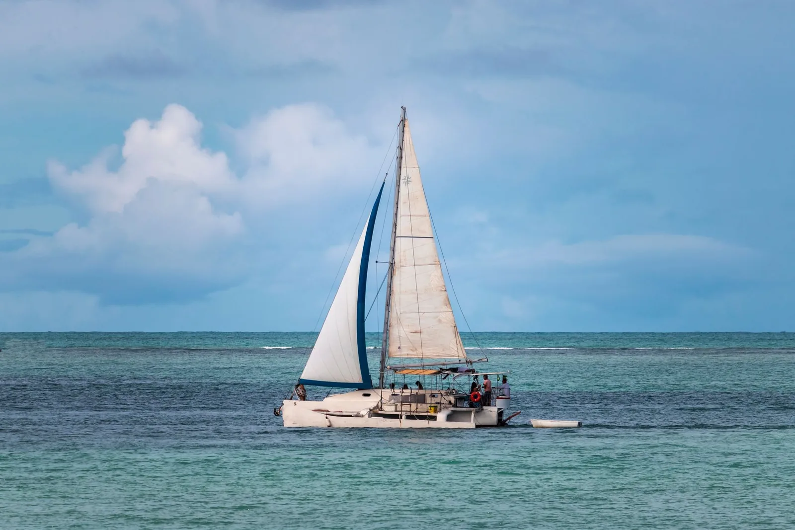 Catamaran à voile blanche sur le lagon turquoise de l'île Maurice, cumulus dans le ciel