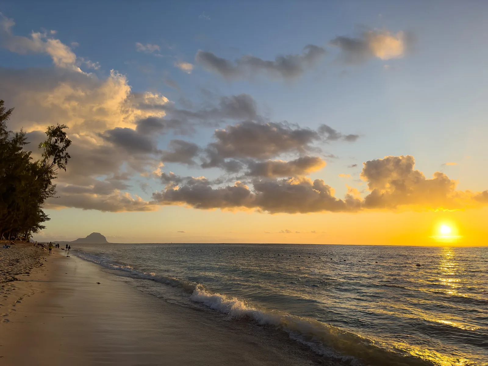 Coucher de soleil sur la plage de Flic en Flac, côte ouest de l'île Maurice, avec une montagne à l'horizon