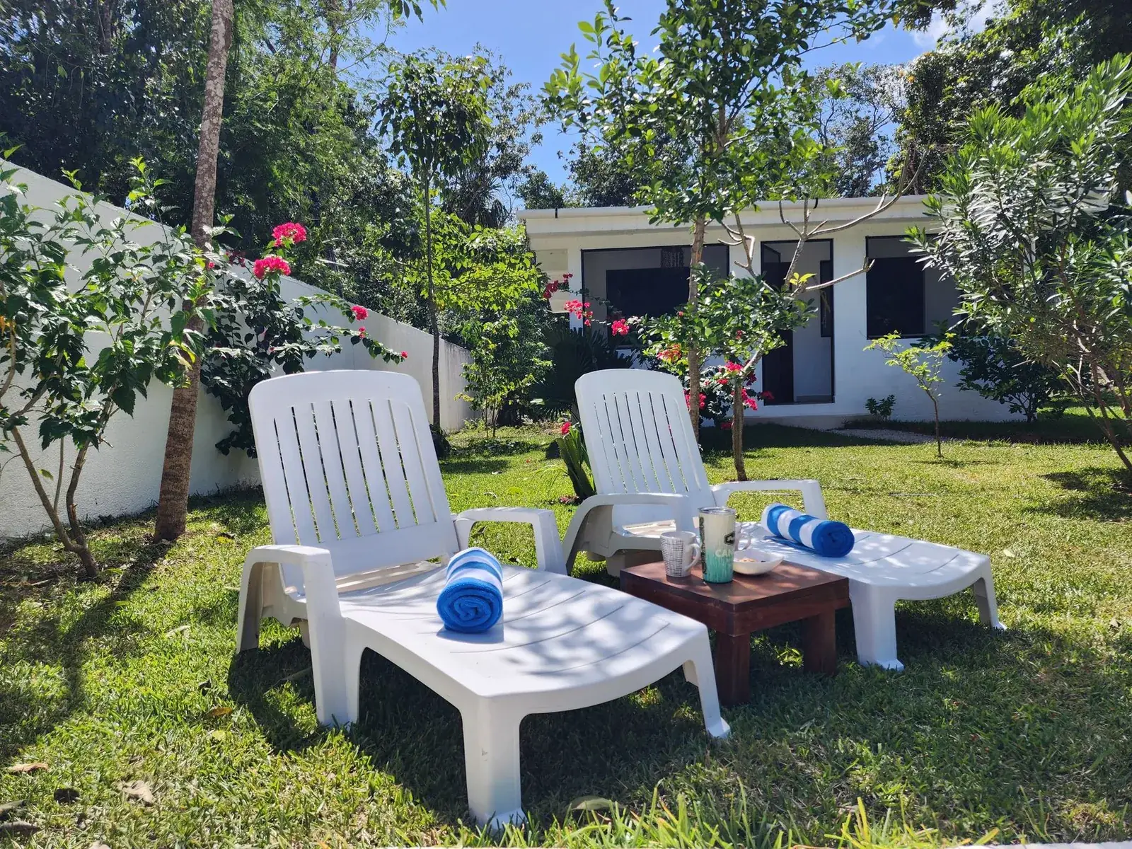 Jardin tropical fleuri avec transats devant un petit hôtel, île Maurice