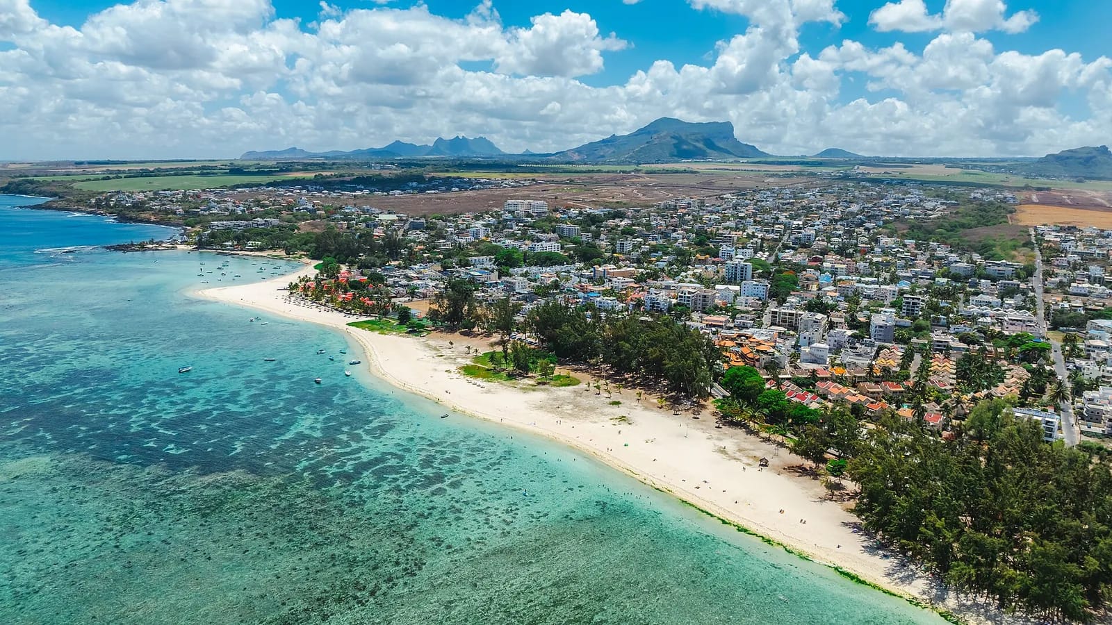 Vue aérienne de la plage de Flic en Flac et de son lagon turquoise, avec les montagnes de l'île Maurice à l'horizon