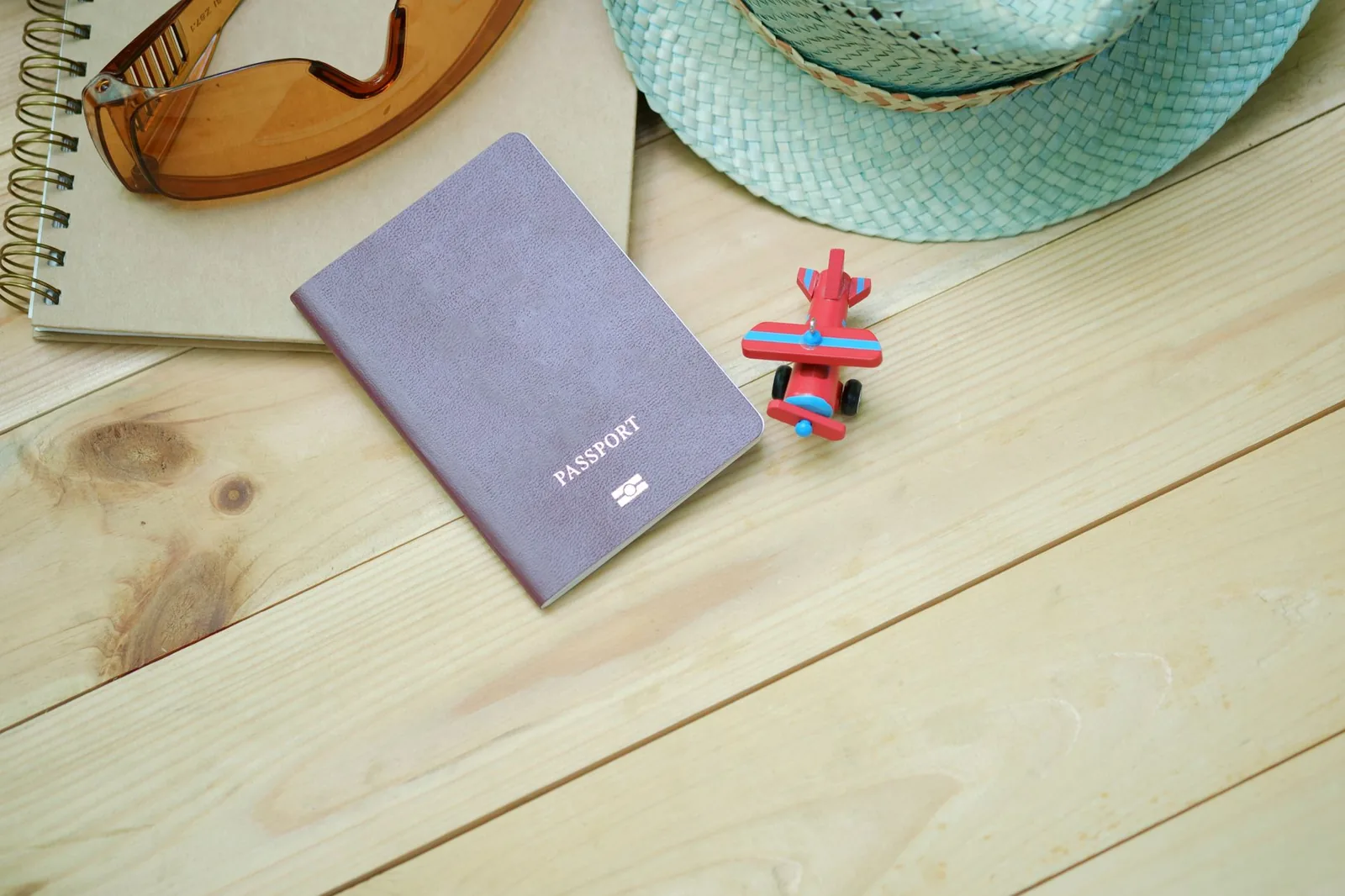 Passeport posé sur une table en bois avec un chapeau de paille et des lunettes de soleil, prêt pour un voyage à Maurice
