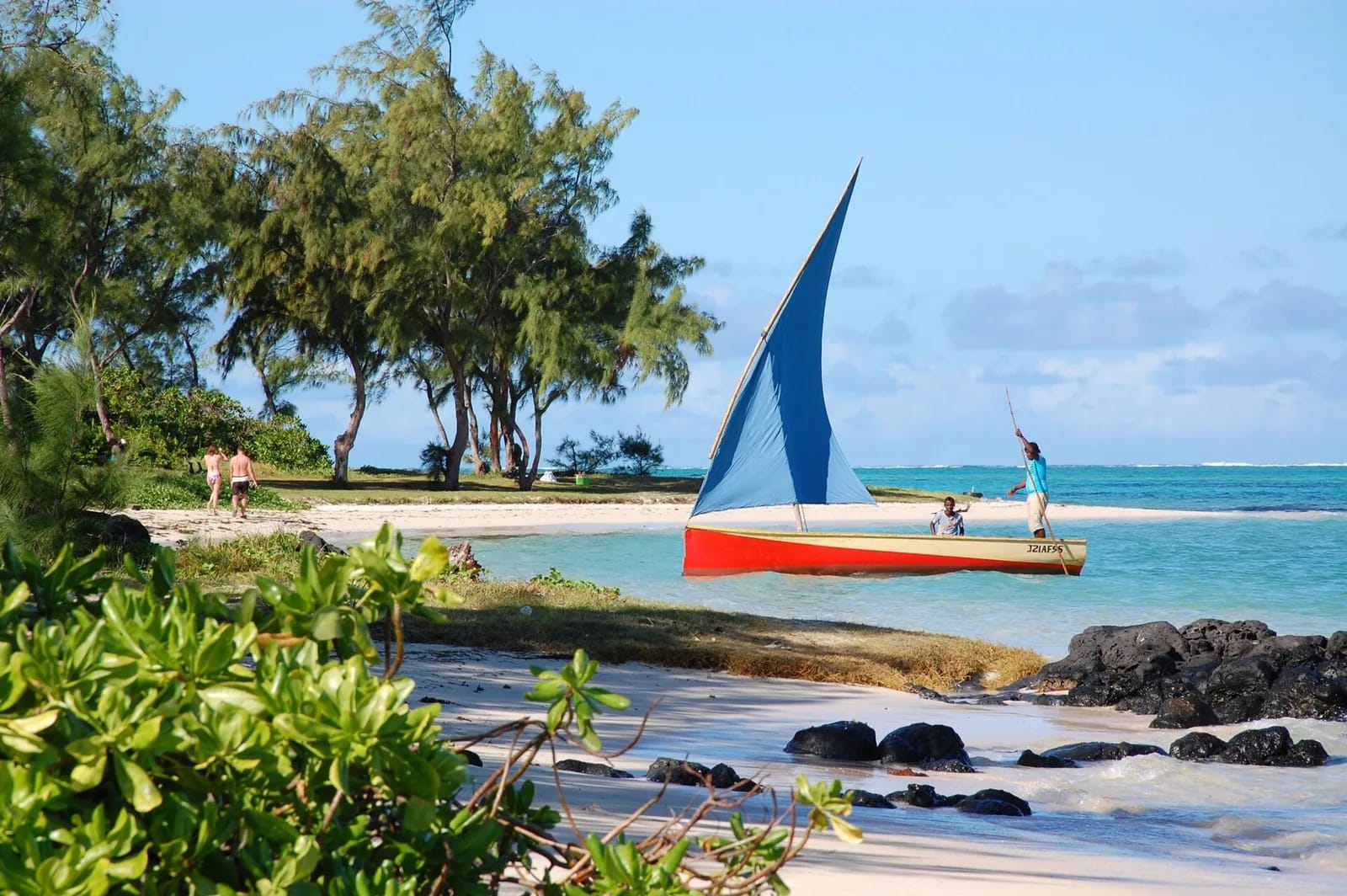Pirogue à voile rouge et bleue sur une plage bordée de filaos, île aux Cerfs, île Maurice