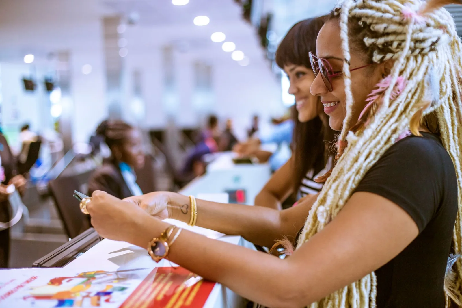 Voyageuse qui consulte son smartphone au comptoir d'un aéroport avant l'embarquement