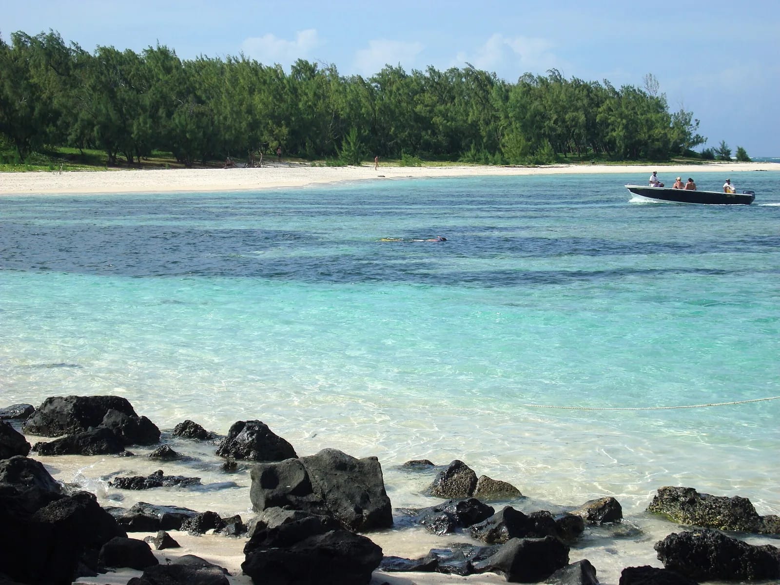 Plage de l'Île aux Cerfs, rochers noirs, lagon turquoise et bateau, côte est de Maurice