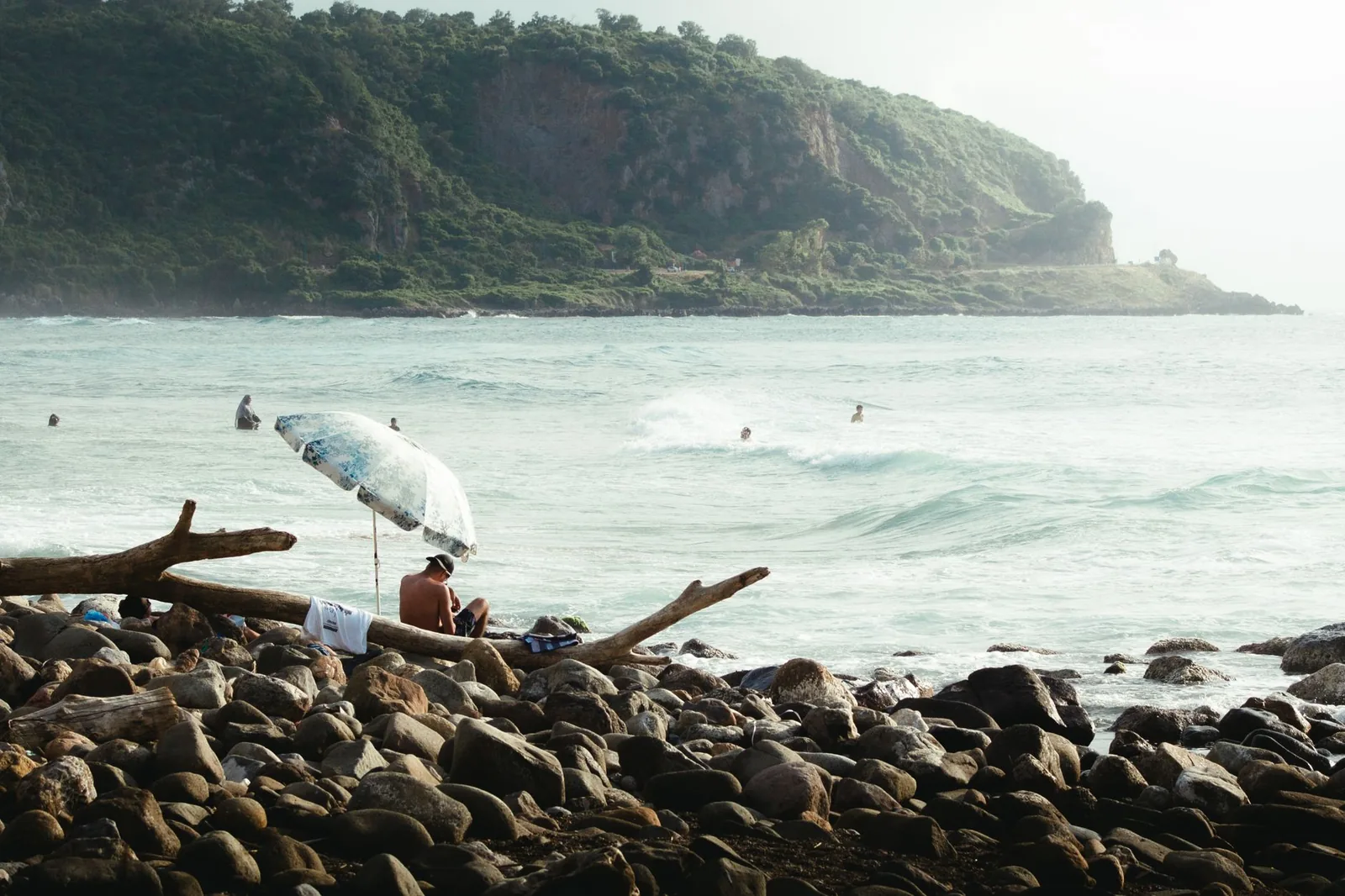 Plage rocheuse battue par les vagues et promontoire boisé, côte ouest de Maurice