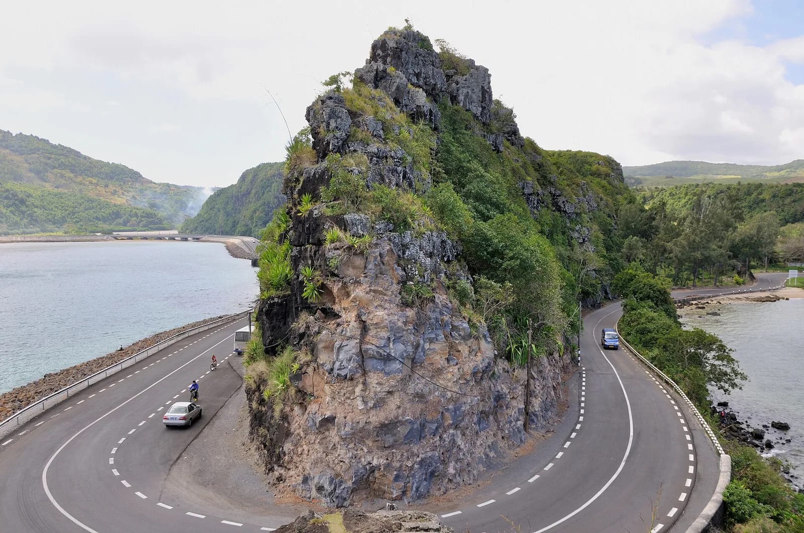 Route côtière en lacet contournant un rocher boisé au bord de la mer, île Maurice