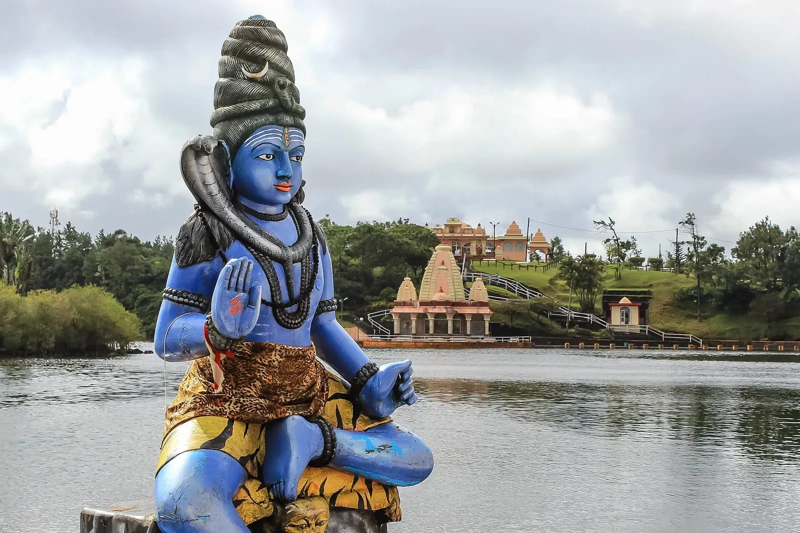 Statue bleue de Shiva au bord du lac de Ganga Talao, avec un temple en arrière-plan