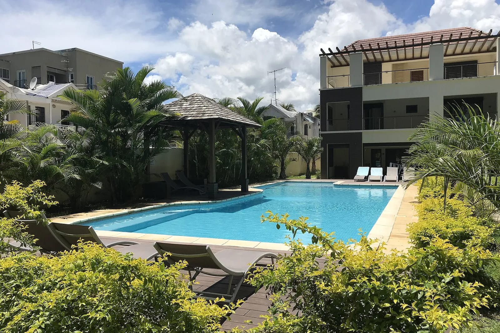 Résidence de vacances avec grande piscine, kiosque et transats parmi les palmiers à Flic en Flac, île Maurice