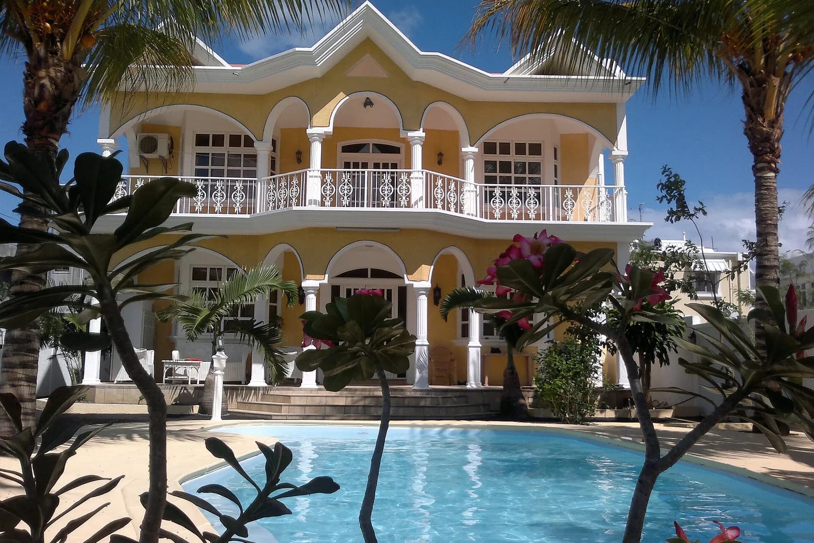 Villa de style colonial jaune avec balcons et piscine à Flic en Flac, île Maurice
