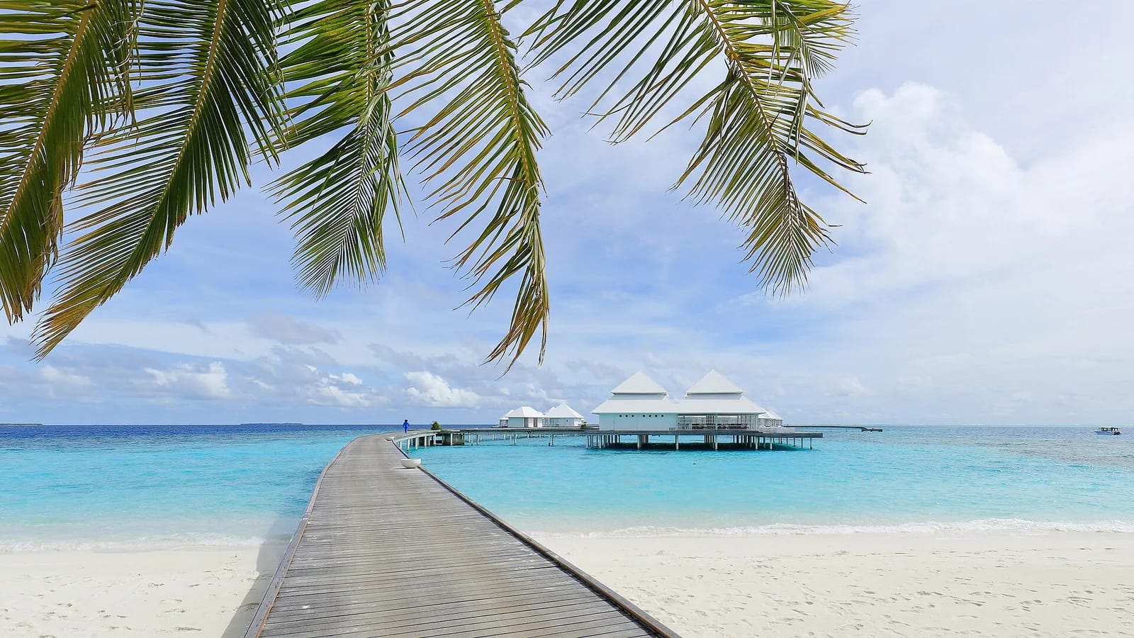 Ponton menant à des villas sur pilotis dans le lagon turquoise d'un atoll des Maldives